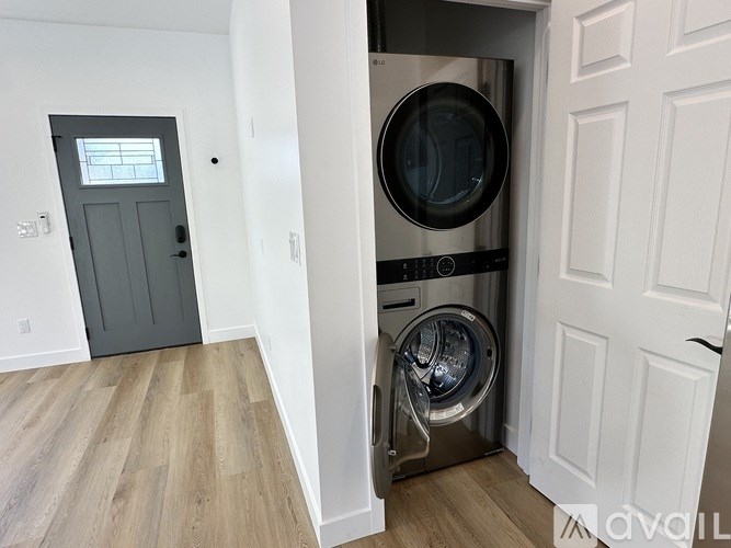 A washer and dryer are built into a wall in a room with wood flooring.