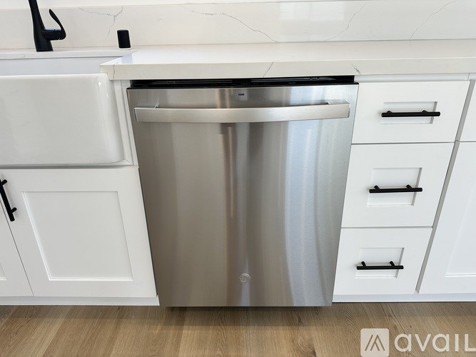 A stainless steel dishwasher is installed in a kitchen with white cabinetry.