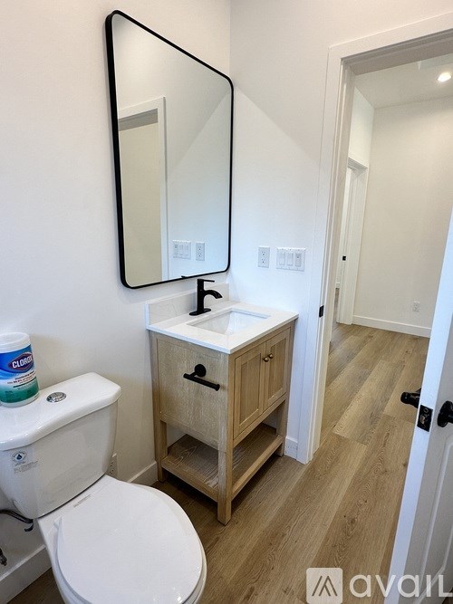 A bathroom with a toilet, sink and mirror.
