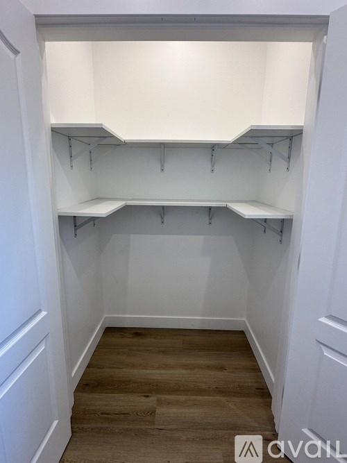 Empty white shelves in a room with wooden floors.