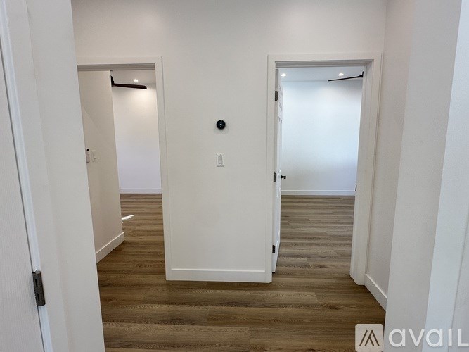 A room with white walls and wooden flooring with two doors.