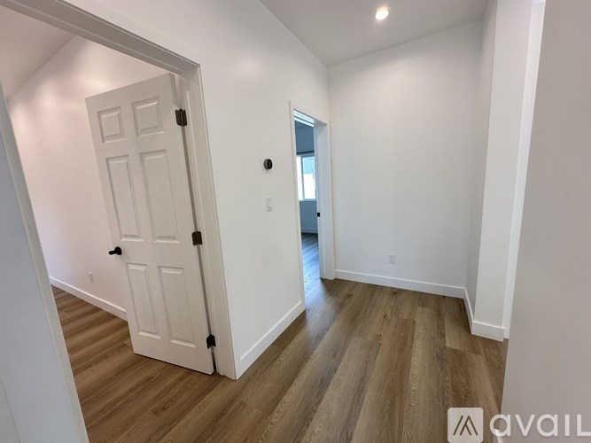 A white door with a black handle is in a room with wooden flooring.