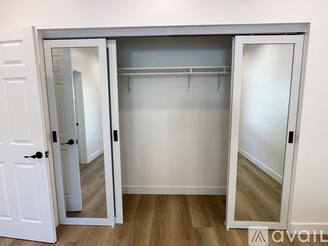 A white closet with a mirrored door is open.