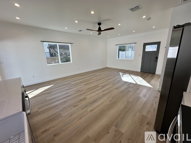 A spacious room with wooden flooring and a ceiling fan.