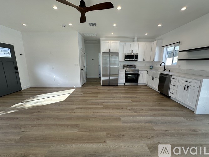 A spacious kitchen with white cabinets and a wooden floor.