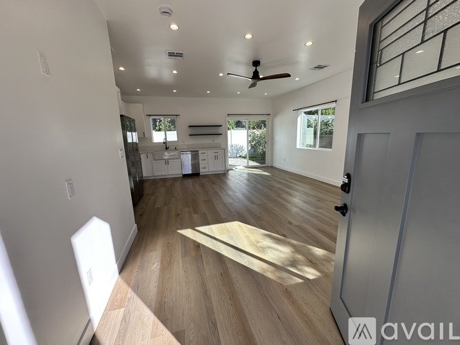 A spacious room with wooden flooring and a ceiling fan.