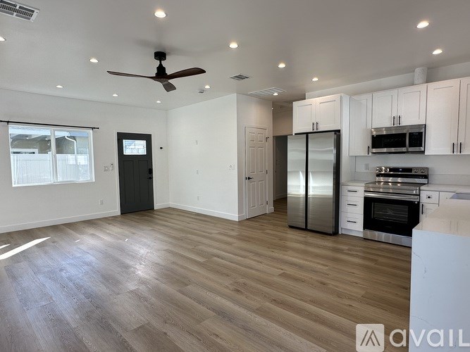A spacious kitchen and living room with wooden flooring and modern appliances.