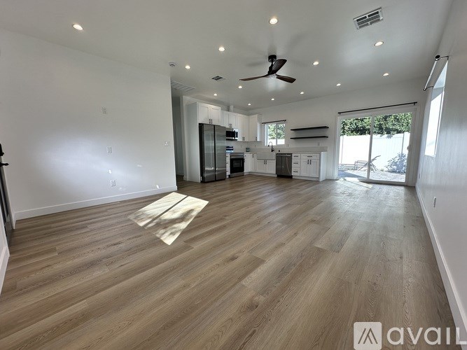 A spacious room with wooden flooring and a ceiling fan.