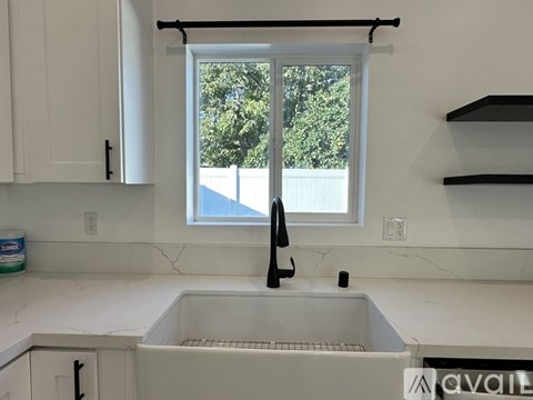 A kitchen with a white sink and a window.