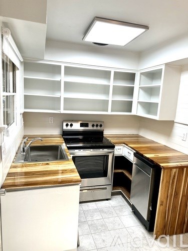 A kitchen with a wooden counter top and stainless steel appliances.