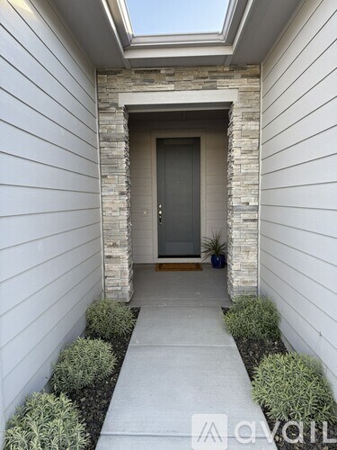 A white house with a grey door and a stone pillar.
