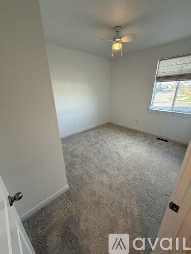 A room with a carpeted floor and a ceiling fan.