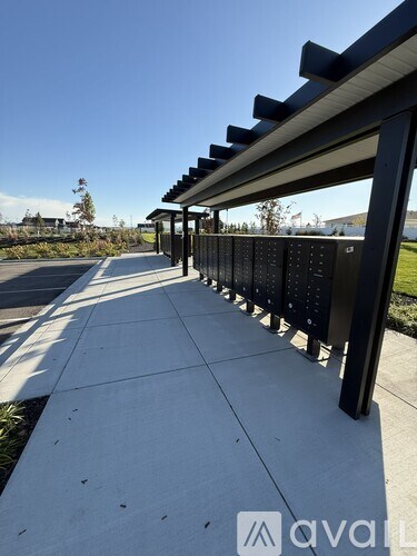 A long black bench with a roof is on a concrete walkway.