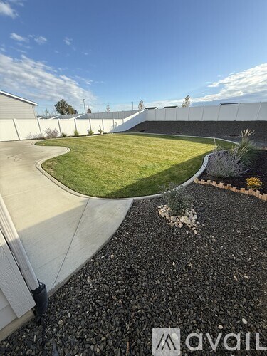 A gravel area with a grassy slope leading to a building.