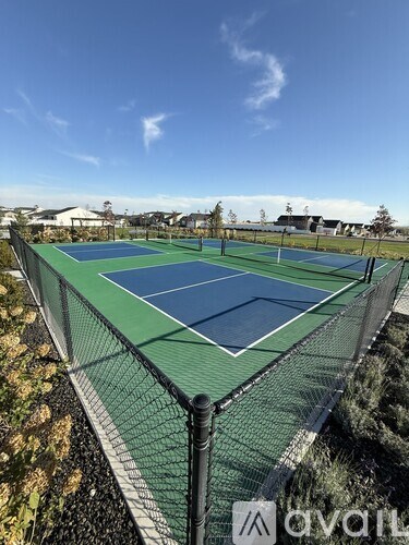 A tennis court with a green and blue surface surrounded by a black fence.