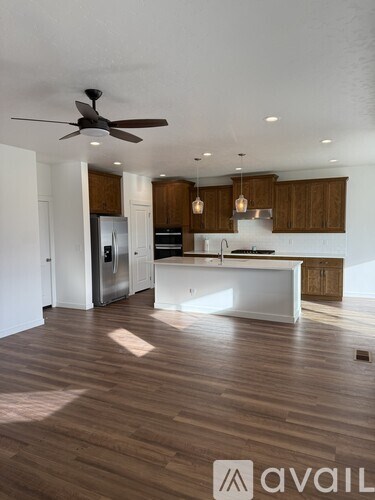 A modern kitchen with wooden floors and a ceiling fan.