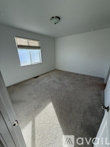A room with a carpeted floor and a window with blinds.