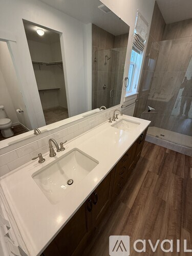 A bathroom with a white sink and brown wood floors.