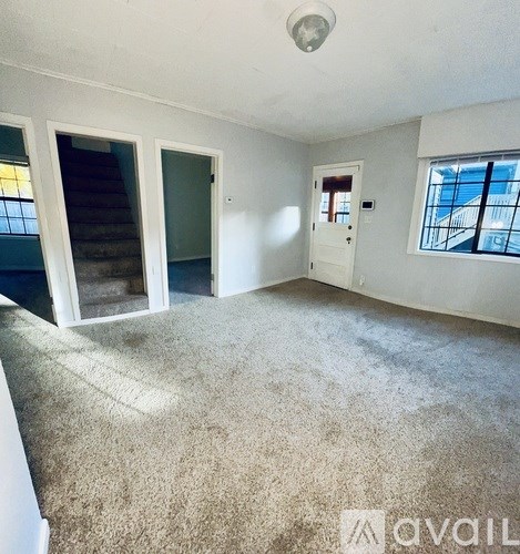 A room with a carpeted floor and a window showing a balcony.