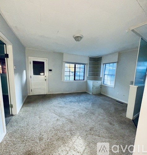 A room with a carpeted floor, a door, and a window.