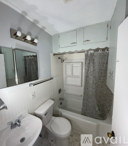 A white bathroom with a toilet, sink, and shower.