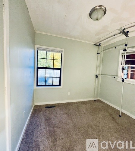 A room with a window and a carpeted floor.