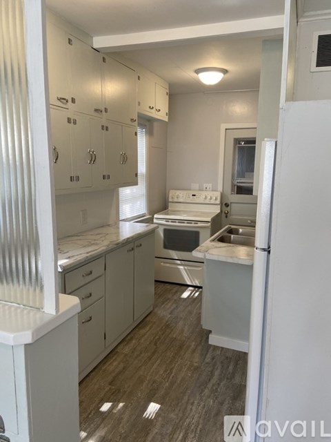A kitchen with white cabinets and a white refrigerator.