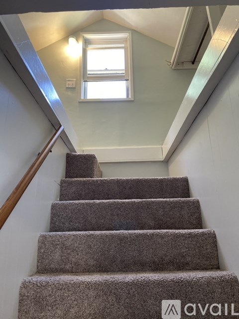 A staircase with a carpeted runner and wooden handrail.