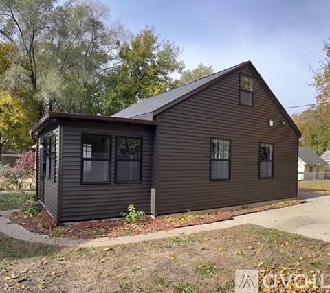 A small house with a brown siding and a dark brown roof.