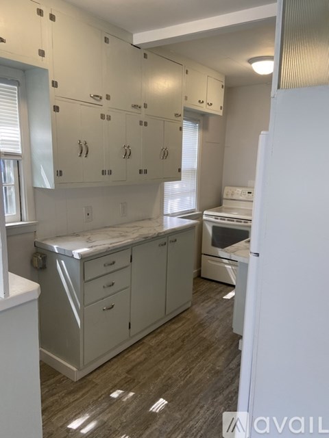 A kitchen with white cabinets and a marble countertop.