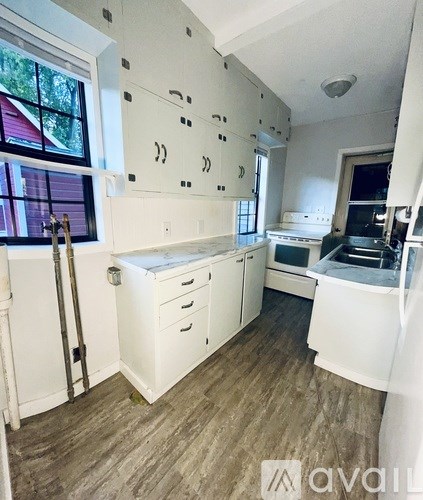 A kitchen with white cabinets and a window.
