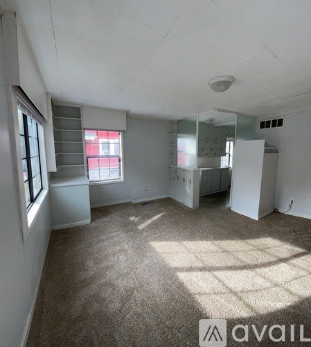 A room with a carpeted floor and a window with blinds.