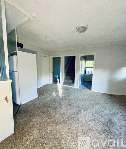 A room with a carpeted floor and a white refrigerator.