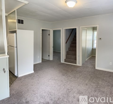 A spacious room with a staircase leading to the second floor.