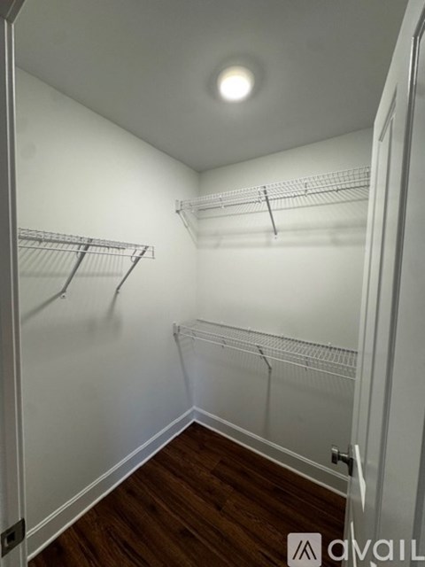 A white closet with a light on the ceiling and shelves for hanging clothes.