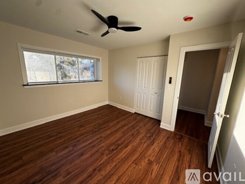 A room with a ceiling fan and wooden flooring.