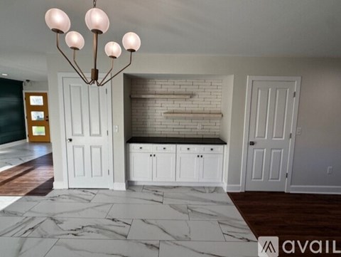 A modern kitchen with a marble floor and a chandelier.