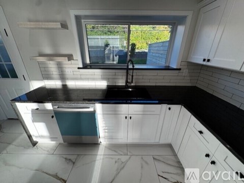 A kitchen with white cabinets and a black countertop.