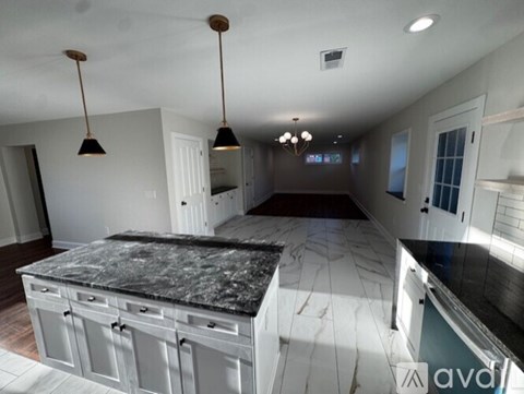 A kitchen with a granite countertop and pendant lights.