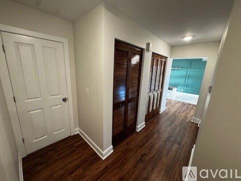 A room with a white door and wooden floors.
