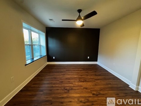 A room with wooden flooring and a ceiling fan.