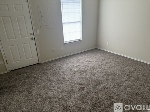 A room with a carpeted floor, a door, and a window with blinds.
