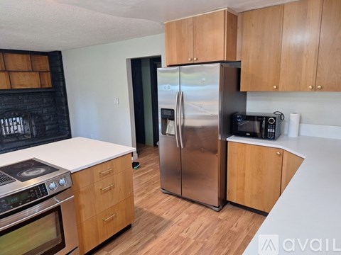 A kitchen with wooden cabinets and a stainless steel refrigerator.