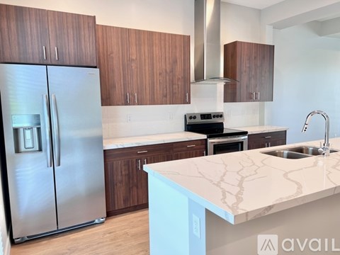 A kitchen with a stainless steel refrigerator and wooden cabinets.