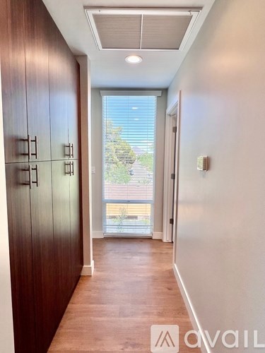 A hallway with wooden floors and a white wall with a door on the right.