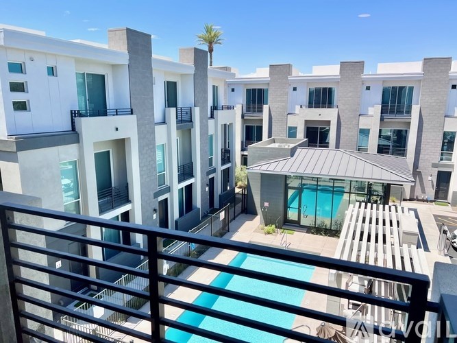 A modern apartment complex with a pool and a palm tree.