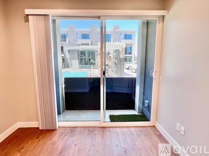 A room with a sliding glass door leading to a balcony with a pool.