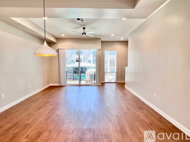 A spacious room with wooden floors and a ceiling fan.