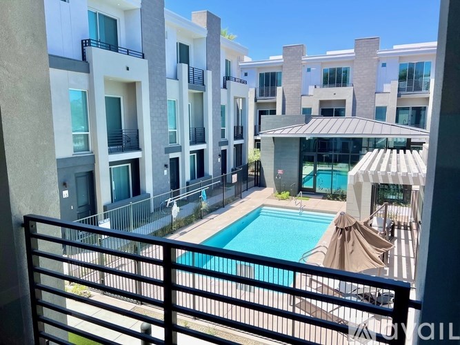 A pool area with a black railing in front of apartment buildings.