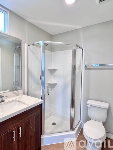 A white toilet sits next to a walk-in shower in a bathroom.